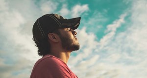 A person standing outside, facing the sun with their eyes closed just taking a moment